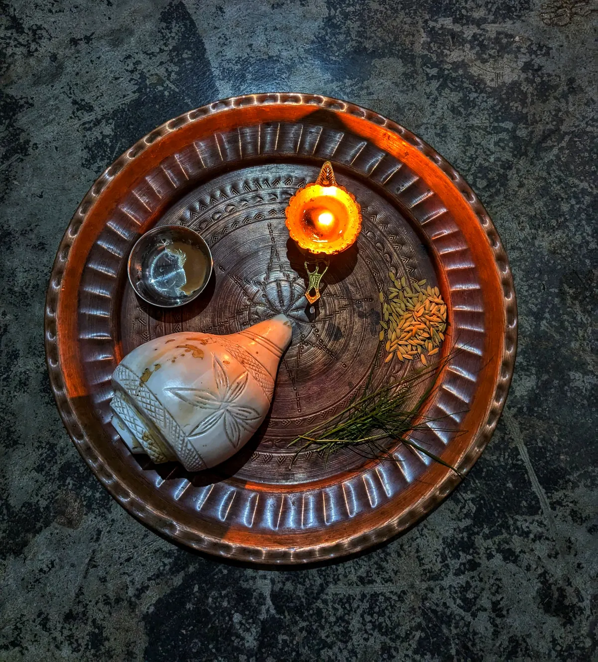 Puja thali with a lit diya, conch shell and offerings for Bhai Dooj