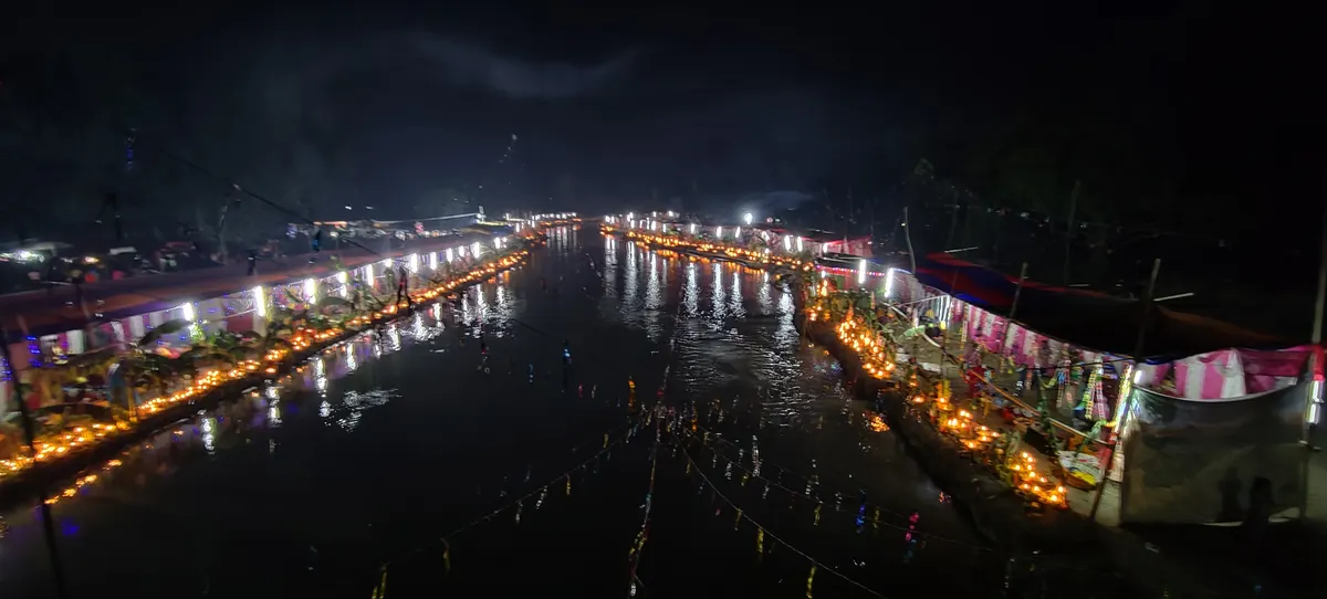 Chhath Puja ghats lit up with lamps along the water at night