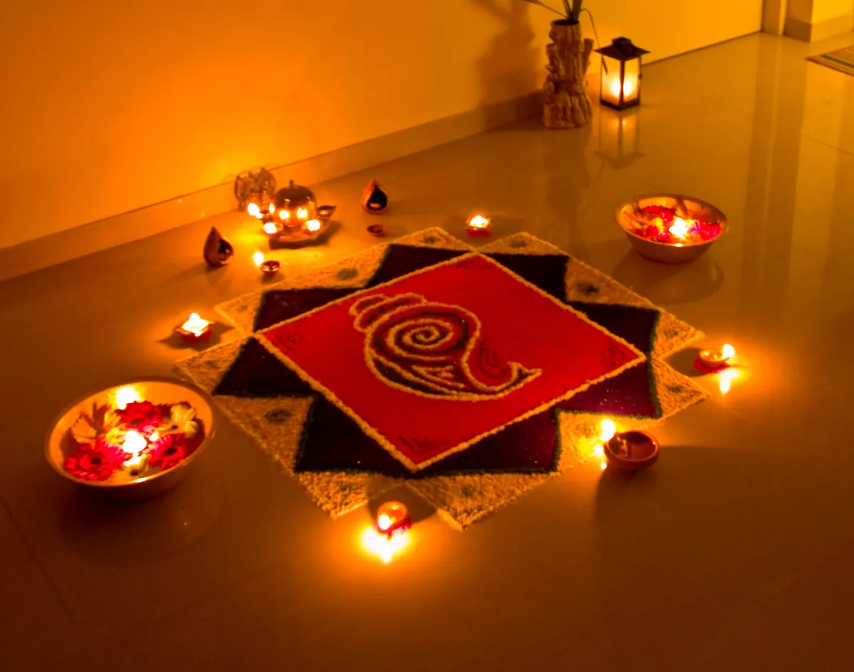 Rangoli ringed with lit diyas on the evening before Diwali