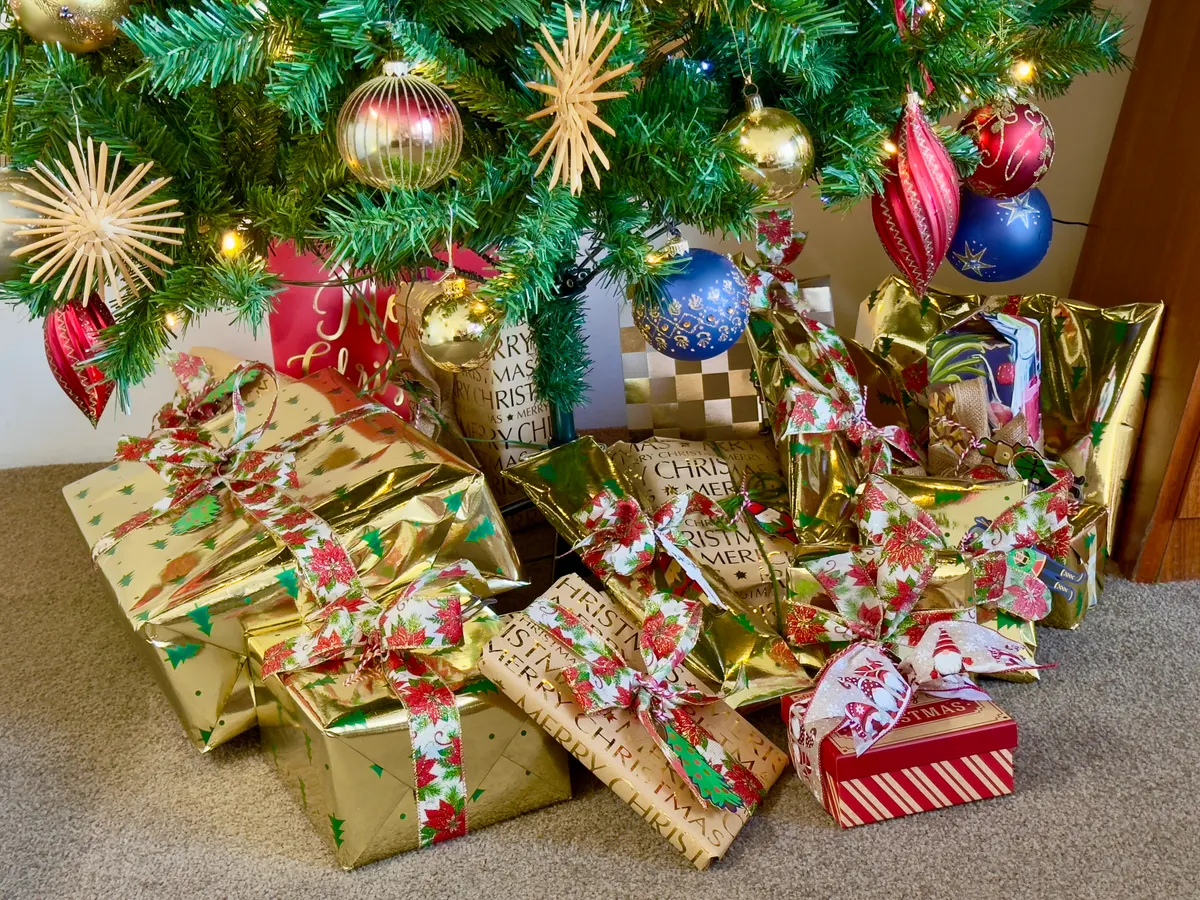 Wrapped Christmas gifts piled under a decorated tree ready for a gift exchange