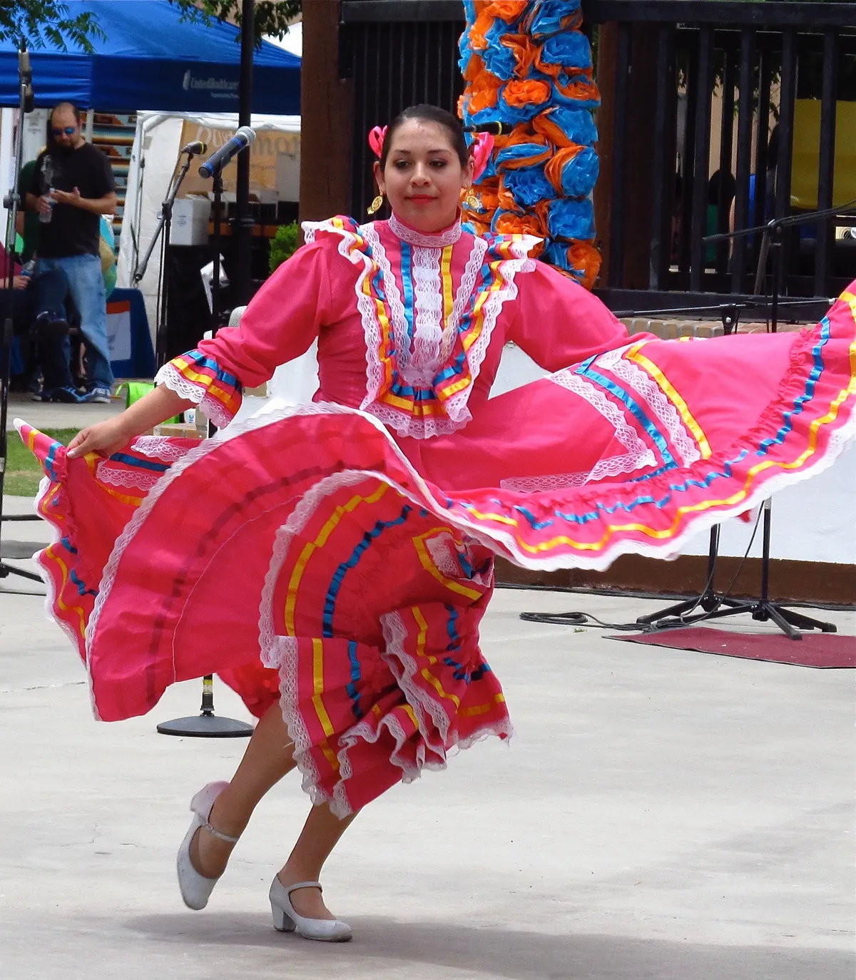 A folklorico dancer twirls a bright pink ribboned skirt at an outdoor Cinco de Mayo festival