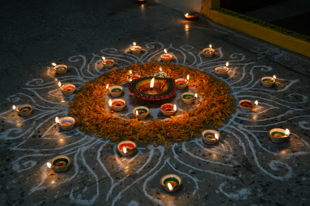 Lit diyas set in a colourful rangoli for Diwali