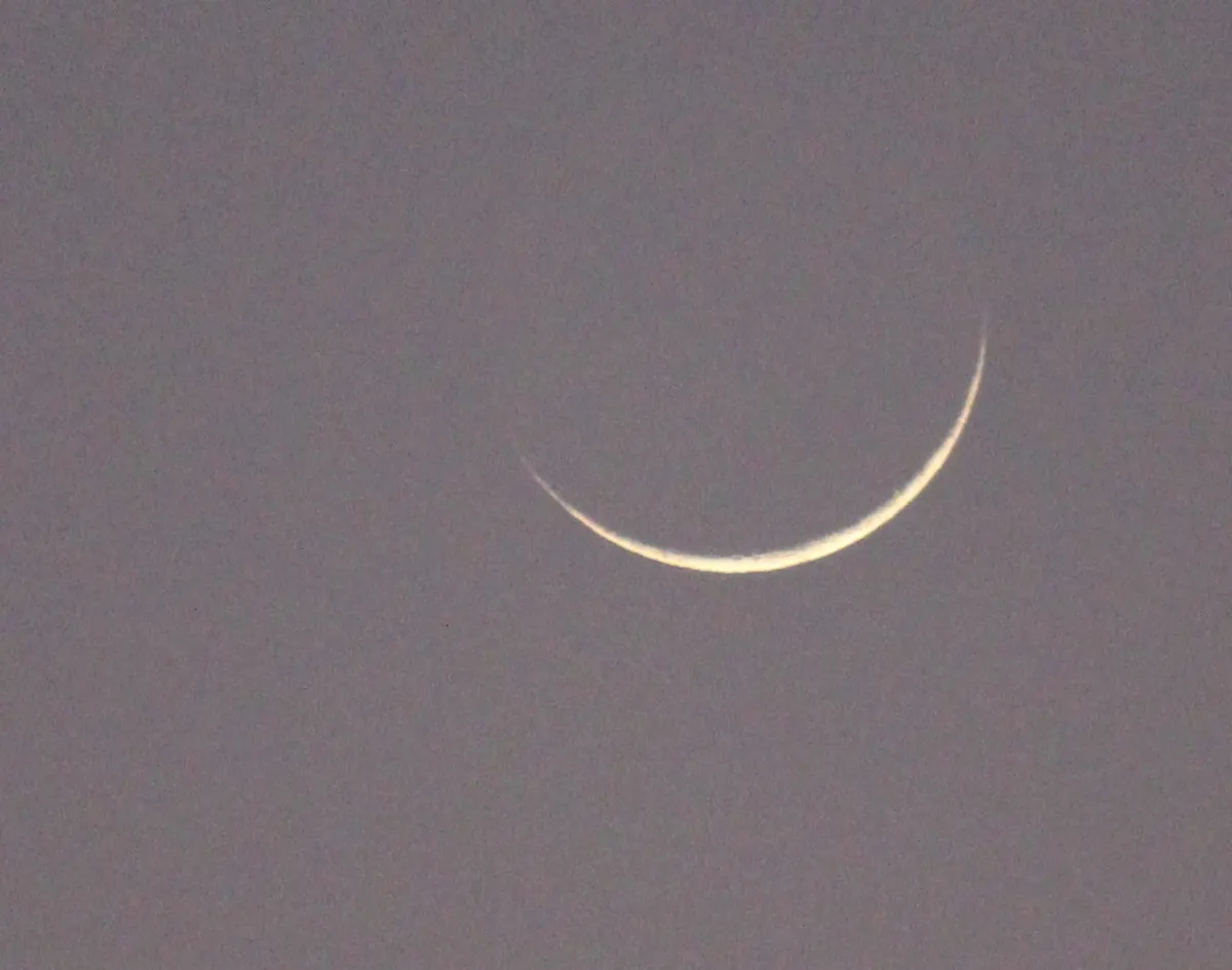 Thin crescent moon in the evening sky on the eve of Eid