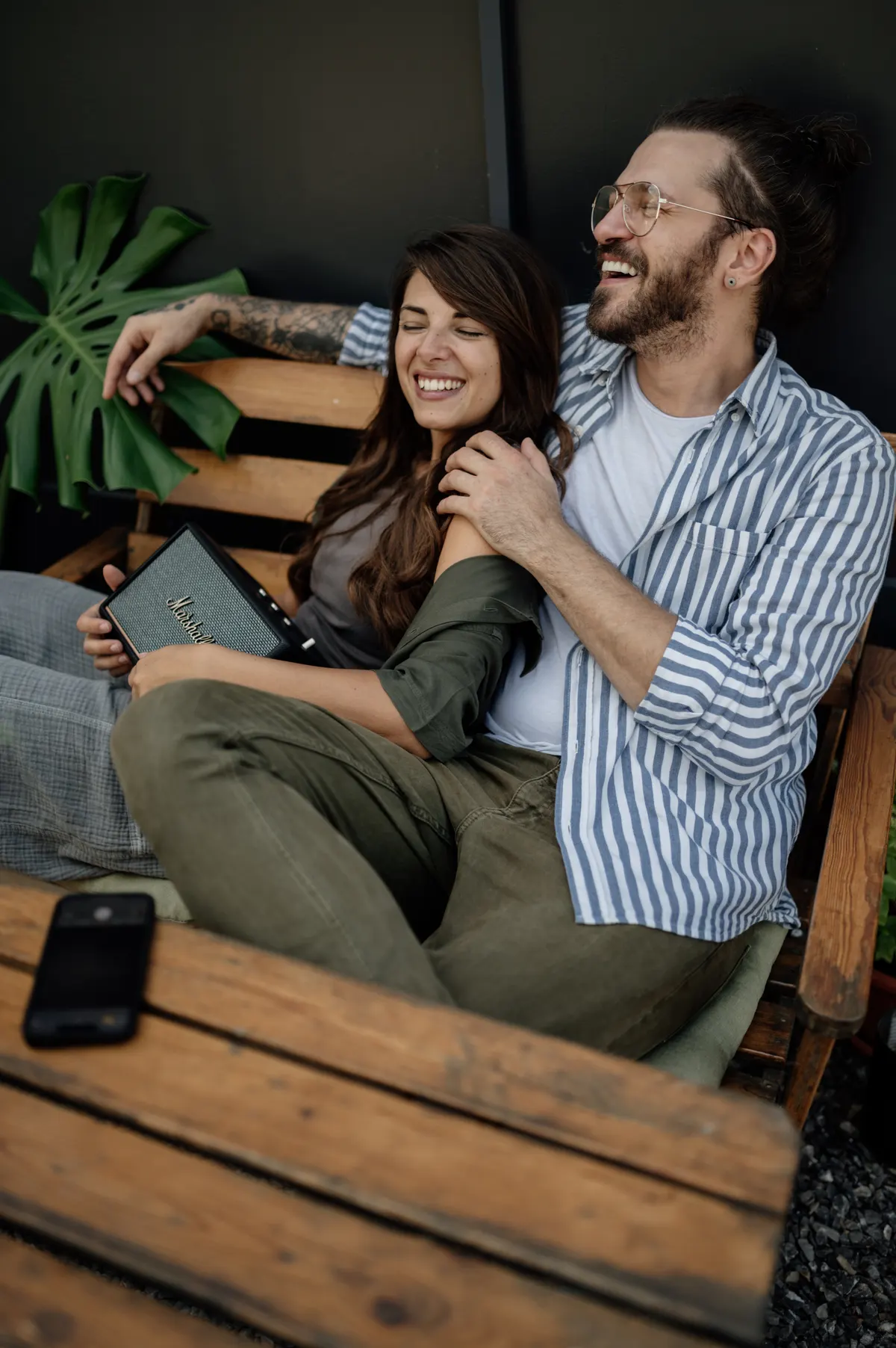 A young couple sitting close on a wooden bench, laughing together