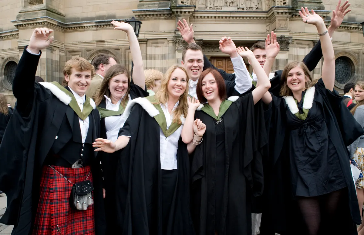 Edinburgh University graduates in gowns cheering outside the old college building