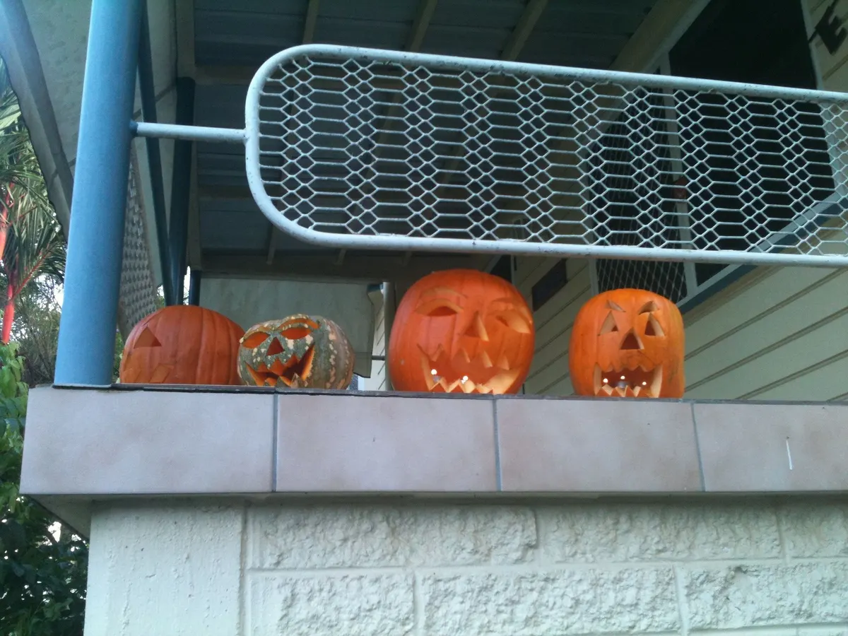 Row of carved jack-o-lanterns on a balcony ledge
