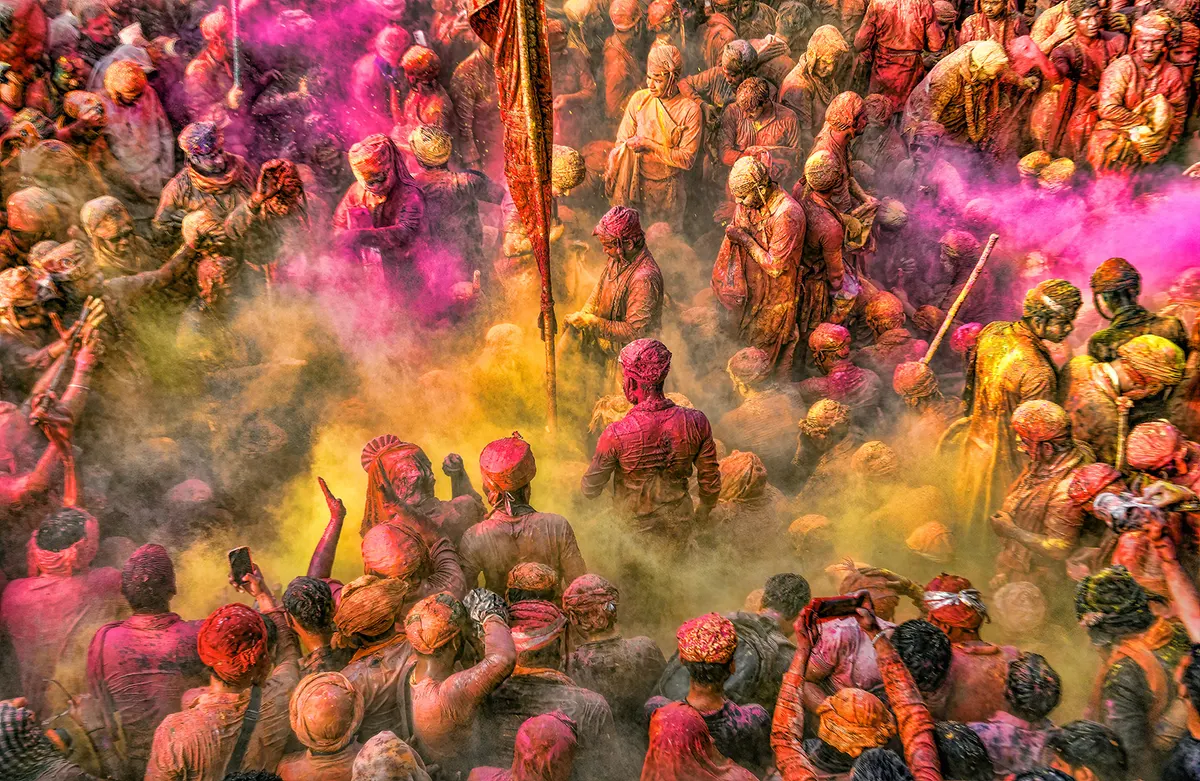 Crowd drenched in pink and yellow gulal during Holi celebrations
