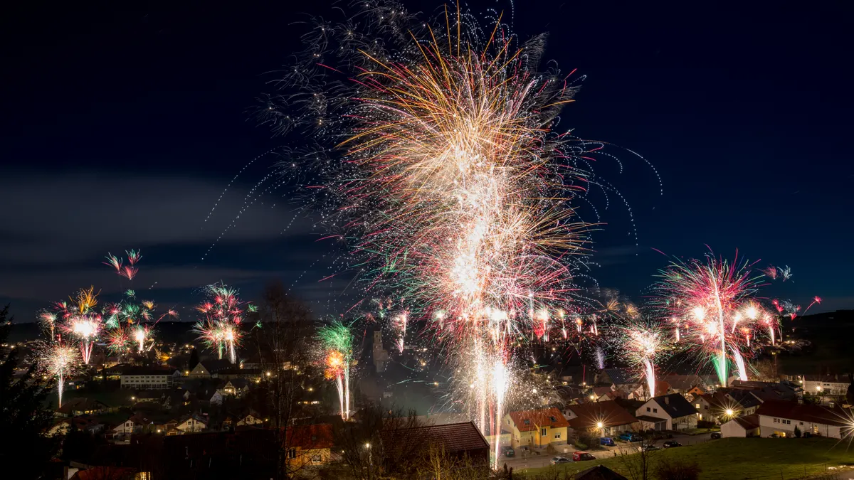 Fireworks rising over the rooftops of a small town at midnight on New Year
