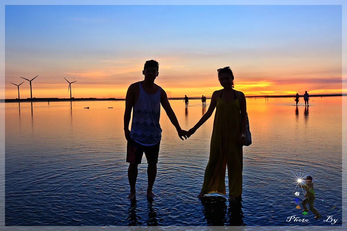 Silhouette of a couple holding hands in shallow water at sunset