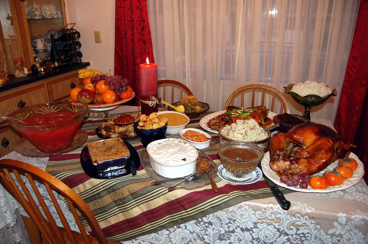 Thanksgiving dinner spread with a roast turkey, sides and pies on a family table