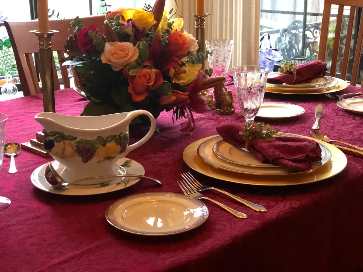 Thanksgiving table set with gold plates, autumn flowers and a gravy boat