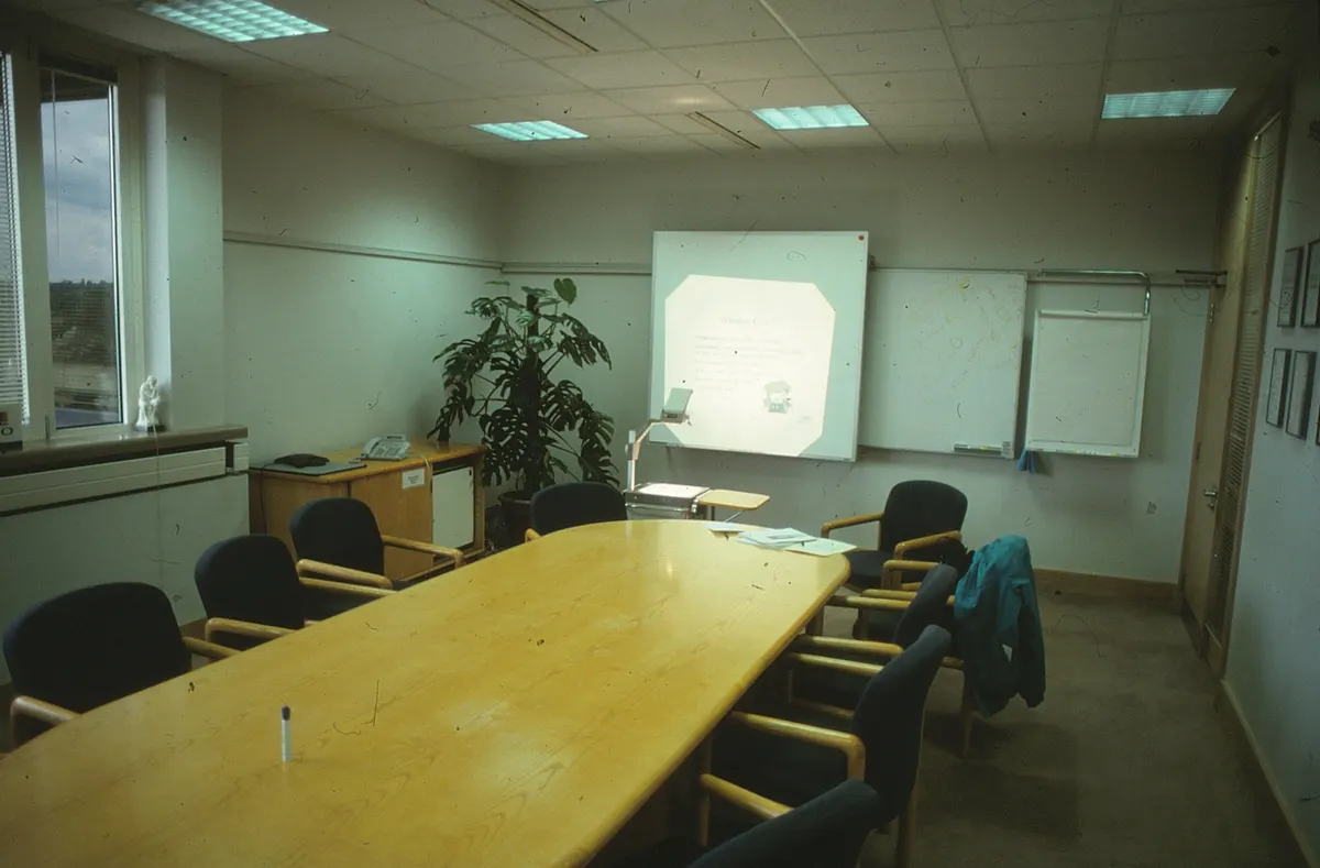 Office meeting room with a long wooden table and a whiteboard