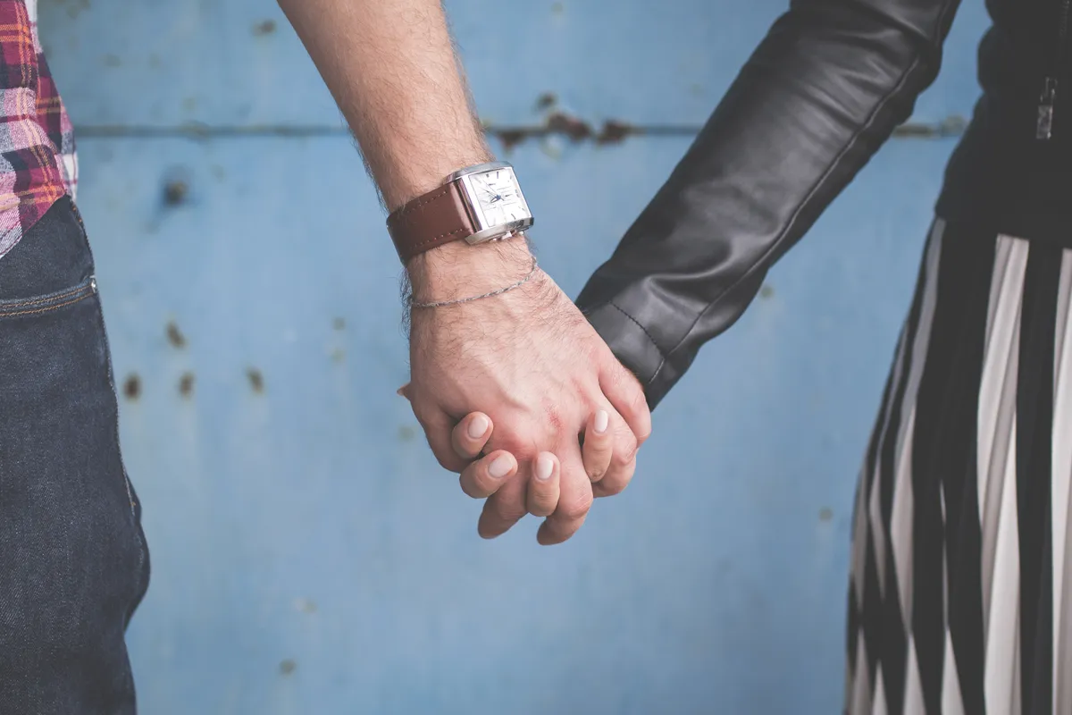 Close-up of a couple holding hands against a blue wall