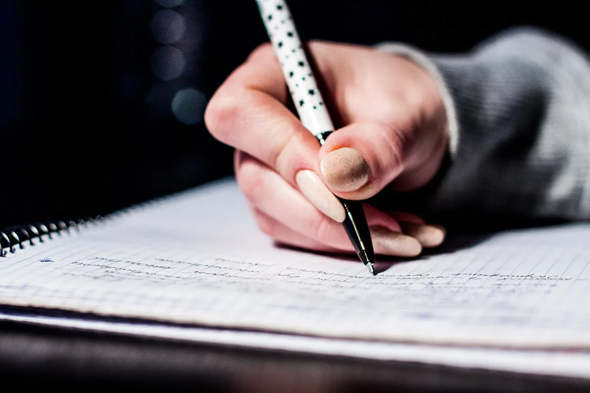 Hand writing notes with a pen in a spiral notebook