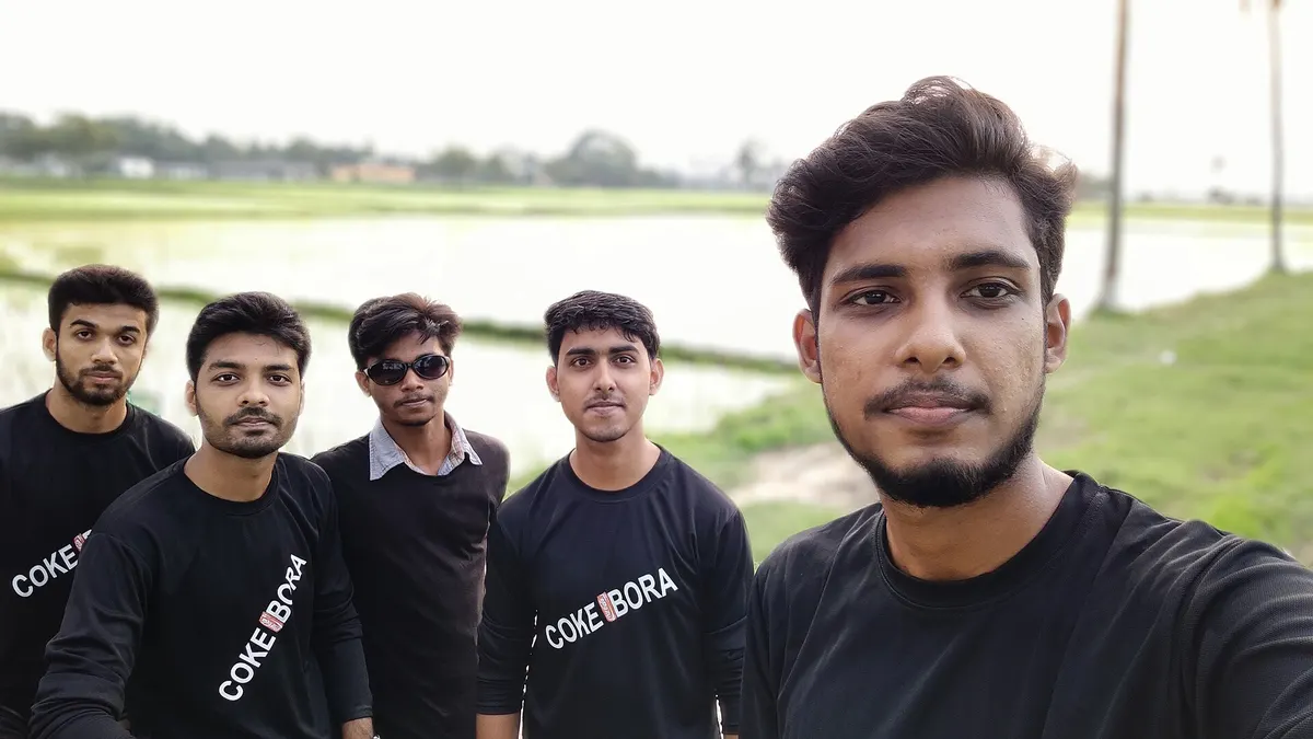 Group of young men taking a selfie beside green fields