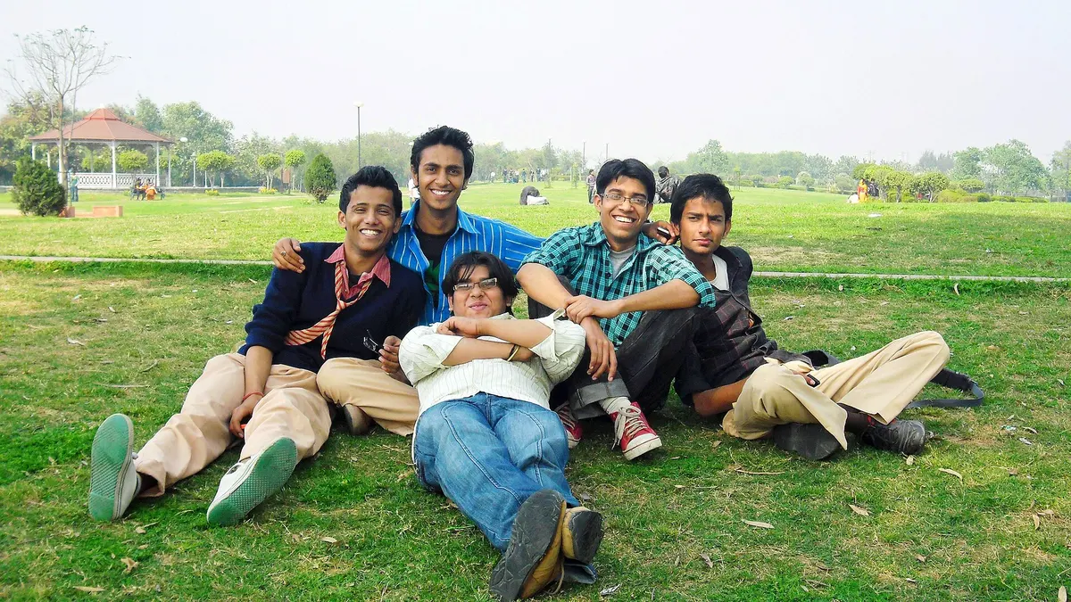Five friends relaxing together on the grass in a park