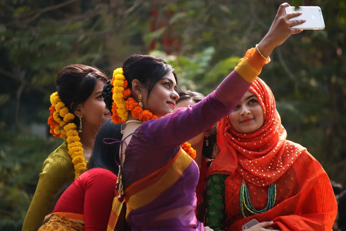 Friends in festive sarees and flower garlands taking a selfie