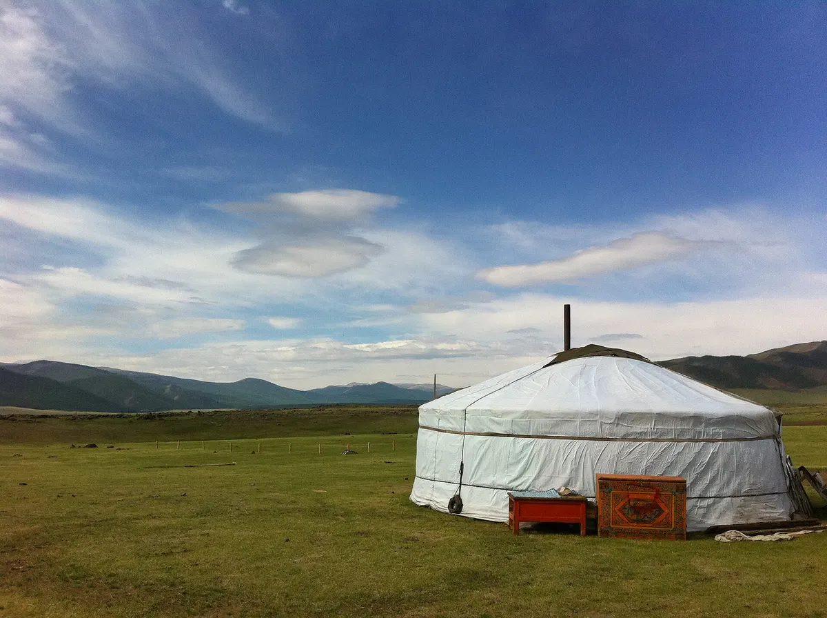 White ger on the open Mongolian steppe under a wide blue sky